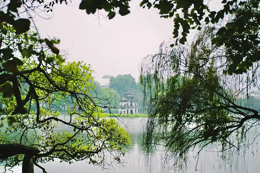 Vue du lac Hoan Kiem à Hanoi avec branches d'arbres au premier plan